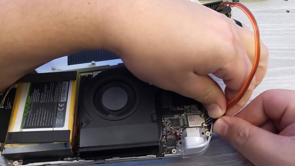 Holding three Dupont cables to three pads on the GPD WIN 4 motherboard.