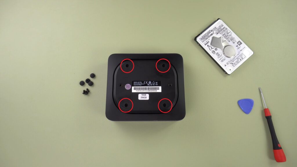 Remove the four rubber feet caps and screws