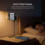 Wall-mounted smart charger beside a bed, with a phone charging on the nightstand.